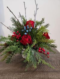 "MADE TO ORDER! This gorgeous Christmas arrangement is made of artificial evergreens, red berries and roses, blue berries and twigs. They are  arranged in wooden round rustic container.  Perfect for your Christmas decor. The arrangement measurements are taken tip to tip 16\"x16\". The container is 3\"x3\". Thank you!"