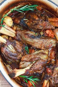 Mediterranean-Style Wine Braised Lamb Shanks Recipe | The Mediterranean Dish. Braising and slow cooker instructions included! Spiced lamb shanks cooked in a red wine and tomato sauce with vegetables, aromatics and fresh herbs! A family favorite for Easter or your next special dinner! See it on TheMediterraneanDish.com