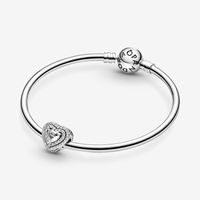 Spread the love with the Sparkling Levelled Hearts Charm. Hand-finished in sterling silver, this piece is inspired by key design features from the Pandora Timeless collection. This charm features an elevated heart-shaped stone at the centre outlined by two rows of clear stones. A cut-out heart pattern features on the sides. Style this piece on your go-to Pandora Moments bracelet with simple charms in sterling silver to make a sparkling statement. | Pandora Sparkling Levelled Hearts Charm in Ster