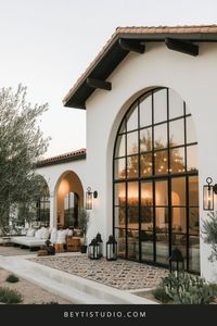 Discover a stunning monochrome farmhouse exterior with Moroccan influences! 🖤🏡 Featuring arched windows, black-and-white details, and rustic beams, this modern farmhouse design exudes elegance. Complete with Moroccan lanterns and patterned tiles, it blends minimalism with exotic charm for the perfect outdoor oasis. #FarmhouseExterior #MoroccanDesign #MonochromeHome #OutdoorLiving #RusticFarmhouse