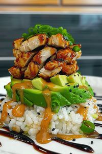 Ingredients:  • 2 cups sushi rice • 2 1/2 cups water • 1/4 cup rice vinegar • 1 tbsp sugar • 1 tsp salt • 2 chicken breasts, diced • 1/4 cup soy sauce • 2 tbsp honey • 2 tbsp mirin • 1 tbsp sesame oil • 1 avocado, sliced • 2 tbsp sesame seeds (black and white) • Fresh cilantro for garnish • Sriracha sauce for drizzling  Instructions:  • Prepare Rice: Rinse sushi rice until water is clear. Cook rice with water in a rice cooker. • Season Rice: Mix vinegar, sugar, and salt. Fold into cooked rice, cool. • Marinate Chicken: Combine soy sauce, honey, mirin, sesame oil. Marinate chicken for 15 minutes. • Cook Chicken: Sauté chicken in a skillet over medium heat until cooked and caramelized, 8-10 minutes. • Assemble Stack: Layer sushi rice in a round mold, top with avocado slices, then teriyaki ch