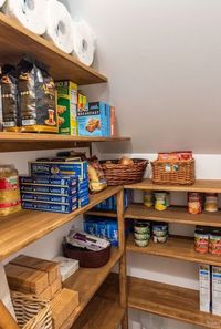 Picture Of a staircase pantry with built in stained shelves, baskets and boxes is a cool and smart idea in rustic style