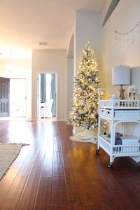 How I added a little Christmas cheer with a simple undecorated, flocked Christmas tree, while we had our home on the market to sell. #christmasdecor #neutraldecor #whitehomedecor #floridahome real estate tips, selling your home, simple decorating tips, realistic looking faux Christmas tree, blanket throw, bar cart, King of Christmas tree.