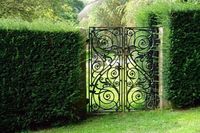 Classical design black wrought iron gate in a beautiful green garden Stock Photo