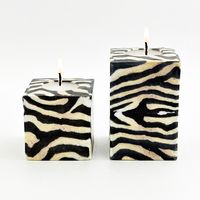 "Immerse yourself in the captivating beauty of our Swazi Cube Candles - a perfect gift for those who value distinctive craftsmanship. Each candle is a unique masterpiece, showcasing mesmerizing patterns meticulously handcrafted into sleek cube designs. Appreciate the individuality of every piece, curated to form a collection of one-of-a-kind works of art. Crafted with care in Swaziland, each Swazi Candle reflects the collaborative effort with skilled artisans dedicated to creating these extraordinary candles for your enjoyment. Dimensions (Inches):  Large: 3.5\"L x 3.5\"W x 5.25\" High Small: 3.5\"L x 3.5\"W x 3.5\" High Mini: 2.2\"L x 2.2\"W  x 2.2\"H Elevate your space with the enchanting glow and artistry of our Swazi Cube Candles. The symbolism captured in each cube candle, with its mo