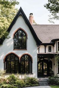 Modern gothic style cottage facade with dark framed arched windows. Check out all of these modern gothic-style cottages that blend dark elegance and contemporary flair to create stunning exteriors.