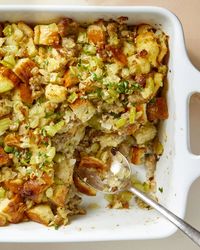 Overhead view of stuffing in a white baking dish with a scoop taken out of the bottom right corner.