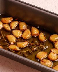 Cooked golden confit garlic cloves in a loaf pan.