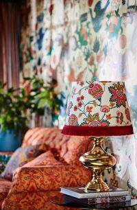 The psychedelic colour palette of MIDSUMMER FLORAL merges bold pinks, pastel greens, vivid yellows, and turquoise blues in a captivating floral print set against a white background. This embroidered fabric cone shade is finished in white fabric lining and red cotton fringes on the base.