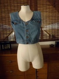 "Cute and cropped 80s vintage denim vest with metal button front, and flap breast pockets. Tank top style. Can be worn alone or as a vest. Excellent vintage condition. By Michael. Made in USA. Tagged a size M. Measured while flat: pit to pit 19\" Across waist 16\" pit to hem 7\""