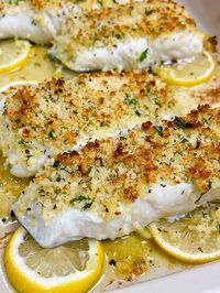 easy lemon garlic baked halibut recipe hero image close up cooked with crispy topping on a bed of lemon