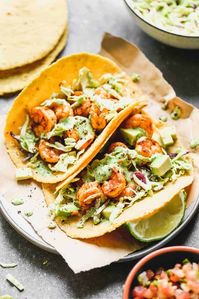 Healthy and easy Shrimp Tacos made with marinated, sautéed shrimp, a simple cabbage slaw, and topped with a delicious creamy cilantro shrimp taco sauce.