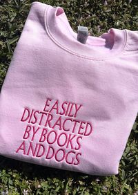 Cuddle up with your favorite book and cozy into our Distracted By Books And Dogs Sweater - where literary passion meets ultimate comfort. The perfect book lover gift or for just yourself! ✨