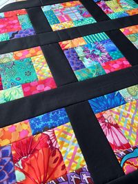 Do you LOVE to quilt, but just don't have the time or energy to shop, cut and piece that perfect fabric? Let me do the top for you and you can quickly finish it up yourself for a fast, handmade gift! QuiltingDiva quilt tops are created with a busy crafter in mind!  Whether you are an experienced quilter that needs to finish a quick gift, or you are learning to quilt and want an expertly pieced and carefully pressed top to work with, my quilts are for you!   All of my quilts are created with the highest quilt shop quality fabrics using brand names you know and trust.   Details: - Fabric: Kaffe Fassett bright prints from multiple collections - Border/sashing: black solid cotton - Measures 38" x 38" - Pattern created by me - Stacy Edell, and available for digital download here: https://www.et