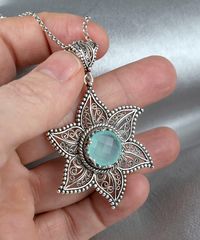 Add a touch of elegance to your jewelry collection with this stunning Sterling Silver Filigree Art Star Pendant Necklace. Handcrafted by skilled artisans, this necklace features six curves of delicate filigree that create a star-shaped pendant, which is set with a mesmerizing aqua blue chalcedony gemstone.  Made from high-quality 925 sterling silver, this necklace is durable, tarnish-resistant, and hypoallergenic, making it perfect for everyday wear. The intricate filigree design adds a touch of