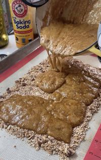 Pouring hot boiled candy onto cookie sheet.