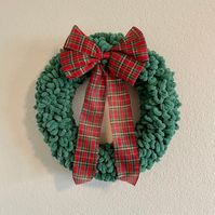 Featuring traditional Christmas colors, this winter wreath will bring warmth and coziness to your home for the holiday season! This wreath is handcrafted with green loop yarn and a large bow on top. The plaid bow is red, green, and gold. This wreath is incredibly soft and cozy and can be displayed all winter long. Its classic Christmas looks makes it easy to pair with other holiday decor! It can easily be hung on a door or wall with a command hook, nail, or wreath hook. This lightweight holiday