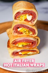 Air Fryer Hot Italian Wraps cut in half and stacked on top of each other showing melting mozzarella cheese, ham, hard salami, pepperoni, banana peppers, and Italian seasoning.