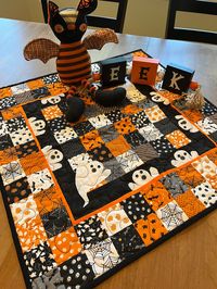 "This quilted table topper is absolutely adorable! Did you know that a group of ghosts is called a \"fright\"? Well hopefully this topper won't give you too much of a fright when displayed on your Halloween table. At 24\" square it is the perfect complement to your Halloween decorating. Center a large decorative candle on it or even better a bowl of candy corn. This has fabric filled with very traditional ghosts, pumpkins, skulls, cats, and webs in orange/ black/grey/white. Buttons for eyes and mouths on these ghosts are all hand-sewn. The backing is black and gray checked, and the toppers are quilted in an allover random pattern.  - This is NOT heat resistant and should not be used as such - Avoid repeated washing. The topper is 100% cotton and can be washed, but is not intended for exten