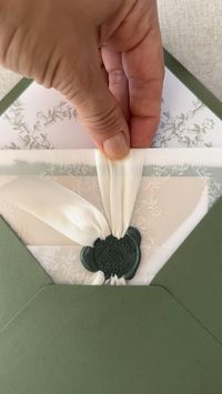 Stunning wedding invitations for an elegant affair. Booking 2024 weddings at the link on this pin! Click to inquire. This suite features, white ink, printed Vellum, green envelopes with white ink, addressing, pearl white silk ribbon, and a dark, green custom wax seal with monogram crest.