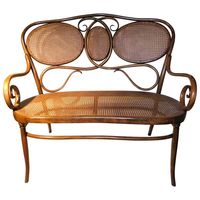 A Gebruder Thonet bentwood bench or settee. A kidney shaped caned seat and back with a bentwood wooden frame. Late 19th century design, originally from Austria, shipping label on bottom shows it was sent to Broadway New York. Beautiful representation of Art Nouveau design. Seat height 18.5 inches.Gebruder Thonet, the furniture manufacturing firm founded in Vienna by Michael Thonet that was greatly expanded by his sons. They perfected the process of bending wood using steam to create curvaceous f