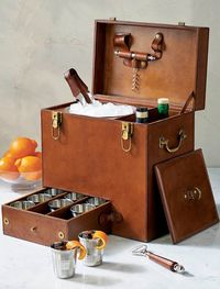 Take your cocktail creations on the road. This sophisticated portable bar features supple buffalo tan leather construction, bar tools, an ice bucket, and two spots for bottles, as well as a separate pull-out drawer with nine cups to drink from.