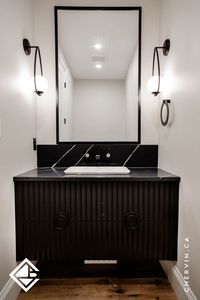 Powder room vanity goals! 🖤 Step into sophistication with this moody masterpiece in #ProjectMorrisonE. The black fluted floating vanity, adorned with unique pulls, creates a seamless and artistic look – a true piece of art! Explore more of this stunning powder room on our portfolio for inspiration!✨ . . . #ChervinKitchen #CustomCabinetry #BlackBathroomVanity #BlackPowderRoom #FlutedBathroomVanity