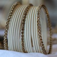 A stylish and versatile way to accessories your wrists is with our Radiant Bangle Set. Curated using our stunning antique gold crystal and white matte bangles. Complement with your outfits or wear alone to add a touch of glamour to your look. ABOUT THIS PRODUCT 15 bangles in total antique gold finish light topaz crystals matte bangles sizes available