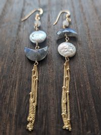 Born under the celestial magic of a lunar eclipse, these earrings embody the wonder of the night sky. Moonstone accent Beads & Labradorite crescent moons, imbued with an otherworldly shimmer, hang alongside luminous white freshwater pearls, resembling a full moon and it's craters. Delicate satellite chains  complete the celestial lunar eclipse look, making these earrings a truly unique and captivating piece. Available in Sterling Silver & 14k Gold Filled