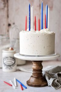 The cutest red white and blue cake for the 4th of July, with red and blue cake layers, sprinkle buttercream, and colorful candles.