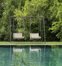 Ethimo's Allaperto Nautic hanging chair offers a splendid choice for outdoor relaxation, especially over stunning views. Its blend of teak wood and recyclable polypropylene rope, crafted in a herringbone pattern, is ideally suited for maritime environments yet adapts beautifully to any outdoor setting.