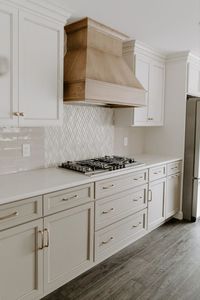 Classic natural kitchen: olive cabinets, stovetop, and wood-stained range hood.