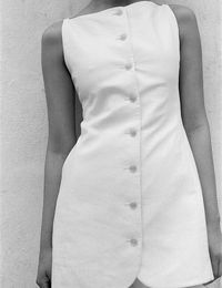 Editor's Notes:A softly sculptural mini-dress featuring a lean silhouette, a bateau neckline and buttons down the front.