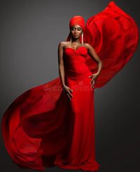 Fashion Woman in Red Dress and Hijab. African Model in Evening long Gown with flowing Silk Fabric over Dark Gray background. stock photos