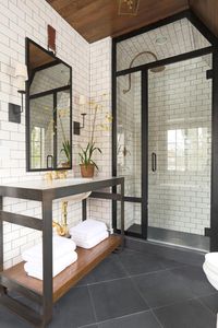 shower with white subway tile, black trim, wood accents