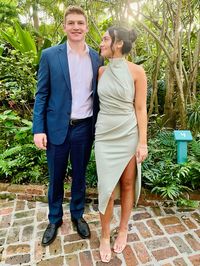 Cocktail wedding attire couple. navy blue suit, Sage green cocktail dress with high neck and slit. Updo with cocktail dress. Spring, summer or fall wedding guest dress