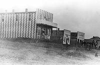 LONG LANE, DALLAS COUNTY, ca. 1910. Long Lane, located in southeastern Dallas County, first had a post office in 1850. Early businesses were located along the muddy road, which later became Highway 32. The two-story building with the curious checkerboard paint pattern housed G. M. Legan Dry Goods. The next building was a barbershop and restaurant, followed by a merchandise store/ post office, a blacksmith shop and a hotel. [SHS of MO-Columbia Photo Collection #026073]