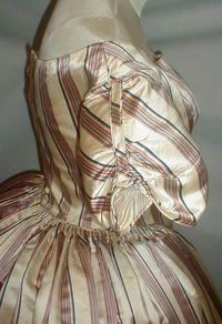 Side view of the 1840s evening dress showing the ombre striped silk more clearly and piped detail to the short puffed sleeves.