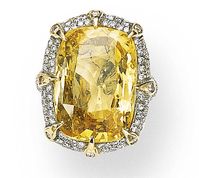 A YELLOW SAPPHIRE AND DIAMOND RING Set with a cushion-cut sapphire weighing approximately 31.03 carats, enhanced by circular-cut diamond prongs, within a circular-cut diamond surround, with pavé-set diamond shoulders, mounted in white and yellow gold