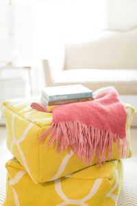 creamy white living room yellow, ivory living room, bright yellow moroccan poufs, pantone primrose yellow, coral pink throw blanket, duck egg blue book, light brown book, ivory carpet, ivory traditional sofa