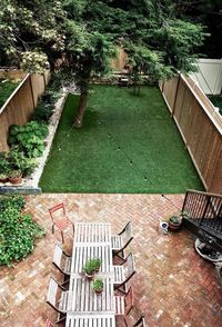 Backyard with bulb lights stringed above. a small patio set, and grass