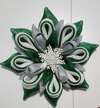 Add a touch of magic to your home with this stunning 20" Snowflake Flower Wreath. Crafted with vibrant emerald green foil mesh, this wreath features eye-catching accents of shimmering silver and crisp white foil mesh, creating a sparkling, frosty effect. At the heart of the wreath, a beautifully detailed white snowflake center completes the design, bringing an extra layer of elegance.   Perfect for the holiday season and beyond, this snowflake wreath will brighten your door or any interior space with its radiant glittering presence.  Whether hanging on your door or displayed in your living room, this wreath will make a statement and spread the spirit of the season throughout the winter months.