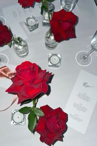 A chic tablescape full of glamour with simple red rose floral arrangements, tea lights and stylish menus designed with hand lettering and a classic font. Moody, dramatic, romantic aesthetic, the perfect vibe for a modern wedding reception, soirée or dinner party.