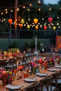 This whimsical + eclectic party was hosted at a sprawling Hollywood Hills Estate. The tennis court was transformed with a variety of lounges offering a travelled aesthetic. Colorful Vietnamese silk lanterns hung over the al fresco dinner tables and floating pool lanterns added a magical touch! Guests enjoyed an Aperol spritz bar and a Mediterranean grazing table in a beautiful garden. Flowers in pottery + brass. Mismatched colored goblets. Photo: Erin Marton, Planning: Art & Soul Events