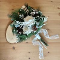 "You have found it! Your perfect winter wedding bridal  bouquet! Imagine your dream woodland wedding - snow softly falling, and you are standing next to the love of your life, holding this pine cone and evergreen bouquet. This bridal bouquet features pure white roses, framed by flocked florals and snow-kissed pine branches. With these specially crafted fabric florals, you can keep your evergreen wedding bouquet for years to come! Here is the must know information: MATERIALS: - Fabric florals - White Lace Ribbon - Cotton ribbon underlay DETAILS: - 20\" tall - 15\" wide - 1 1/2\" diameter (stem) FLORALS INCLUDED: - White Roses - White Flock Florals - Lamb's Ear - Pine Branches - Iced Pine Branches - Pine Cones - Flocked Pine Cones IMPORTANT NOTE: Because this is the off season at my supplier