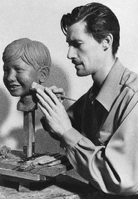 John  Carradine was an excellent side-line sculptor. Photo shows him putting the finishing touches on the head of his five year old son, Bruce.