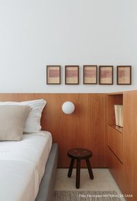 Quarto de casal com painel de madeira como cabeceira tem luminária de teto ao lado da cama e mesinha de cabeceira verde.