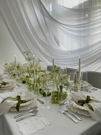 Wedding table setting, white tablecloth, white table napkins, wedding table, white candles on the table, exquisite table setting, table setting with white flowers, white flowers in a vase, table setting with bows, current trend for bows, bows, grapes on the table, сhiffon dome over the wedding table