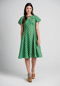 Fall in love with springtime in this gorgeous green A-line dress from Timeless London! Made from a flowy woven fabric with an all-over white daisy print, this vintage-inspired dress features 2-tiered flutter sleeves, a stylish keyhole neckline with tie-string closure, a flattering princess seamed bodice with delicate shirring at the bust, and a flowy knee-length skirt with handy side pockets.