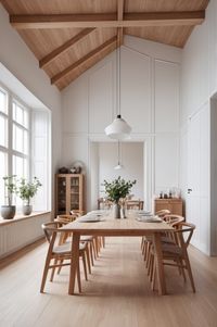 This AI designed dining room embodies Scandinavian elegance with its vaulted ceiling and natural wood accents. The exposed wooden beams add warmth, while a long oak dining table serves as the focal point, surrounded by matching wooden chairs with woven seats. Large windows flood the room with natural light, illuminating the soft white walls and minimalist decor. The natural wood tones harmonize with the crisp white backdrop, complemented by subtle greenery. Modern pendant lights provide soft illumination, creating a cozy yet airy atmosphere, perfect for both casual meals and elegant gatherings.